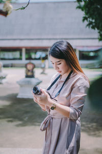 Woman photographing while standing on mobile phone