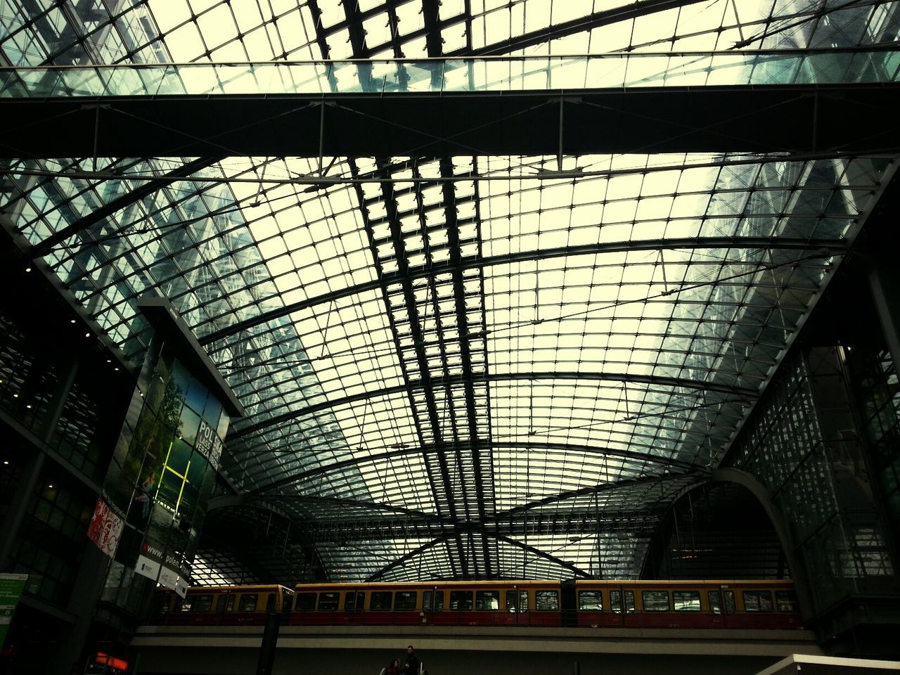 indoors, architecture, built structure, ceiling, transportation, low angle view, public transportation, railroad station, glass - material, modern, rail transportation, interior, illuminated, railroad station platform, window, railroad track, transparent, city, no people, connection