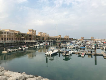 Sailboats moored at harbor against buildings in city