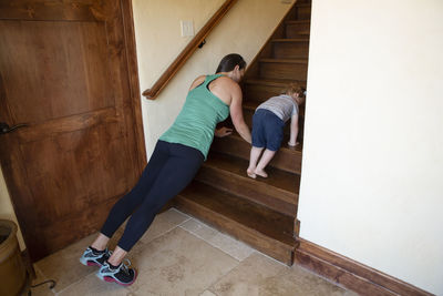 Mother and son practicing push-ups on wooden steps at home