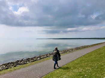 Rear view of man on sea against sky