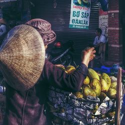 Rear view of person selling mangoes on street market