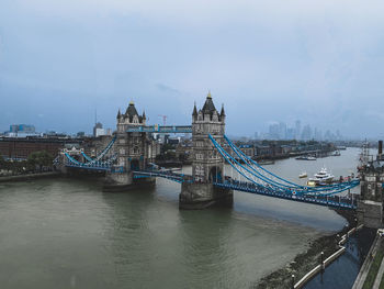 Bridge over river in city against sky