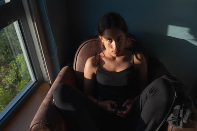 Young woman sitting on sofa looking at camera