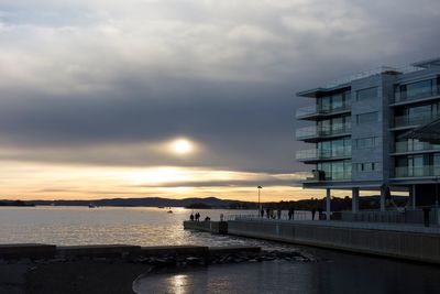 Scenic view of sea by buildings against sky during sunset