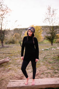 Full length of woman standing on bench against field