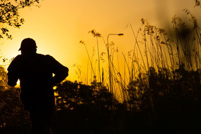 Silhouette man standing on field against sky during sunset