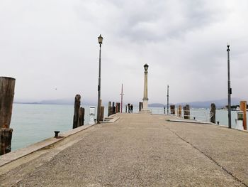 Street by pier on sea against sky