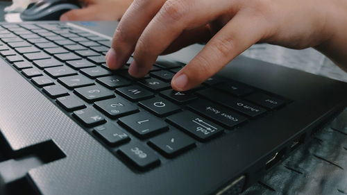 Cropped image of hand typing on keyboard