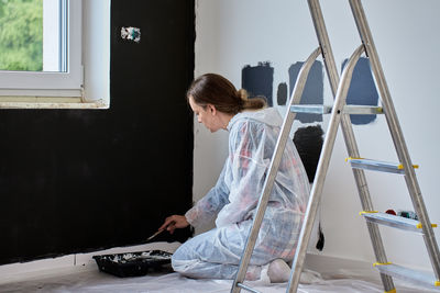 Rear view of woman sitting on window