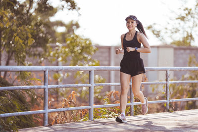 Full length portrait of woman standing against railing