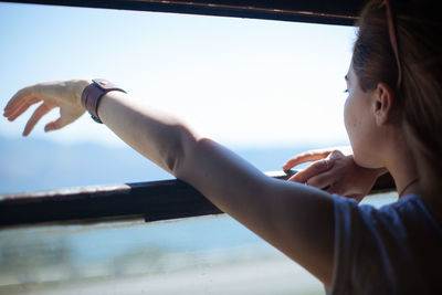 Portrait of woman holding camera against sky