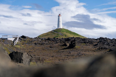 Lighthouse by sea against sky