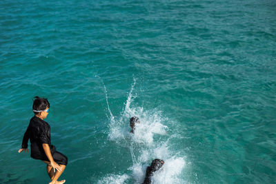 Boy jumping in sea against sky