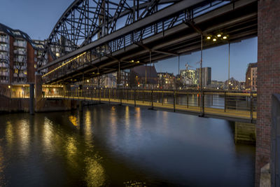 Illuminated bridge over river in city at night