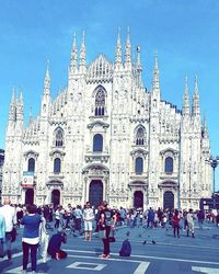 View of people in front of church against blue sky