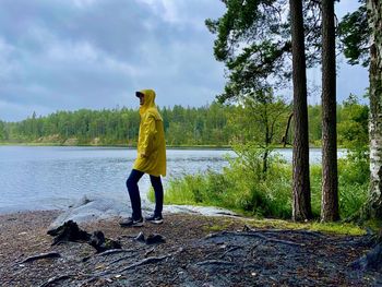 Rear view of man standing on riverbank against sky