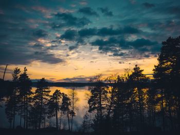 Silhouette trees by lake against sky during sunset