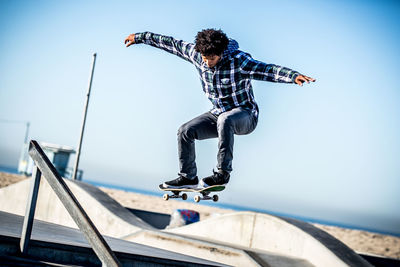 Low angle view of man jumping against sky