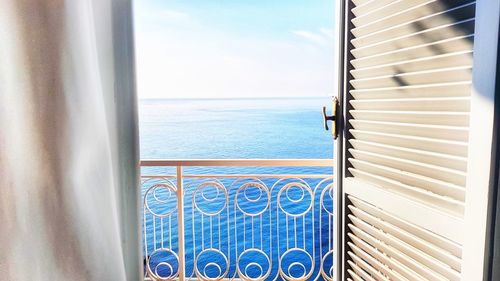 Swimming pool by sea against sky seen through window