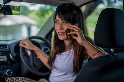 Young woman using mobile phone in car