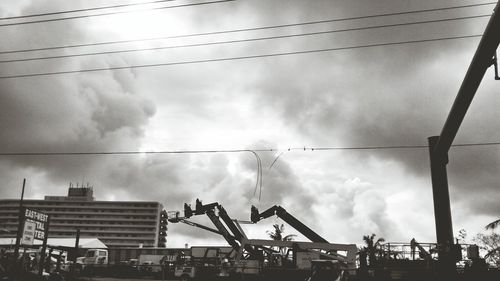 Low angle view of power lines against cloudy sky