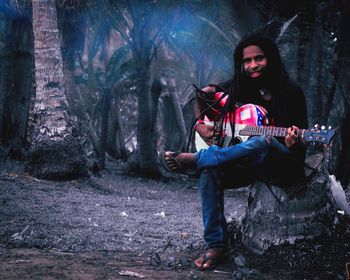 Man holding camera while sitting on land in forest