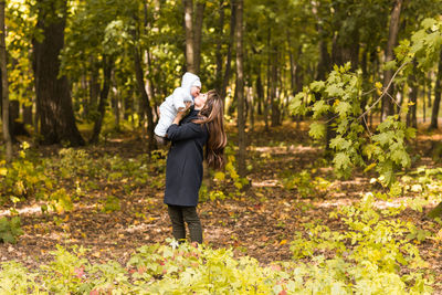 Full length of woman standing amidst trees in forest