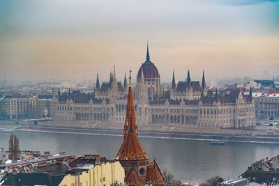 High angle view of hungarian parliament building by danube river against sky during sunset