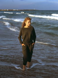 Young woman looking away while standing at beach