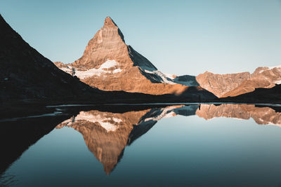 Reflection of mountain range in lake against clear sky