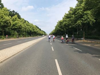 People on road against trees in city