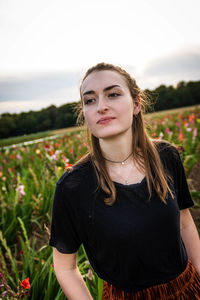 Portrait of beautiful young woman standing on field