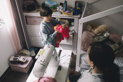 High angle view of boy with warm clothing talking with mother at home