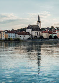 Buildings by lake against sky in city