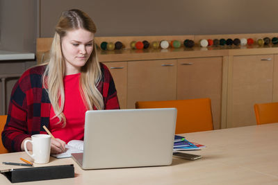 Businesswoman using laptop while sitting at table in office