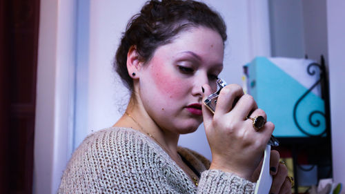 Portrait of young woman holding cigarette at home