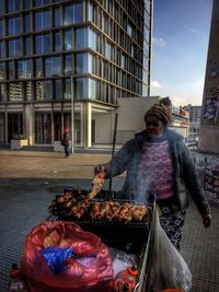 Woman having food in city against sky