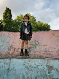 Full length portrait of girl with painted face standing against wall