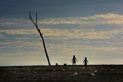 Silhouette of woman standing on landscape at sunset