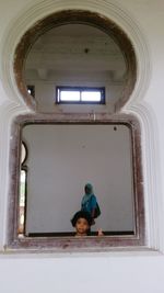 Rear view of man and woman standing against window