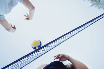 Low section of man holding basketball hoop against clear sky