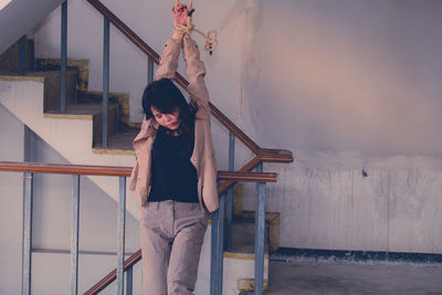 Woman with umbrella standing on staircase