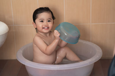 Portrait of shirtless boy sitting in bathroom