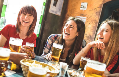 Beautiful young women drinking beer at table in restaurant