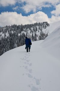 Rear view of person on snowcapped mountain against sky