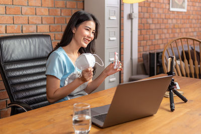 Young woman using mobile phone while sitting on table