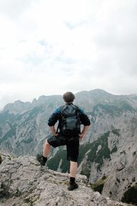 Rear view of man looking at mountains against sky