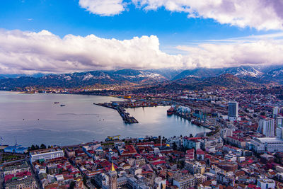 High angle view of city by river and buildings against sky