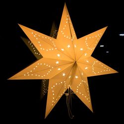 Close-up of illuminated star shape decoration against glass in darkroom